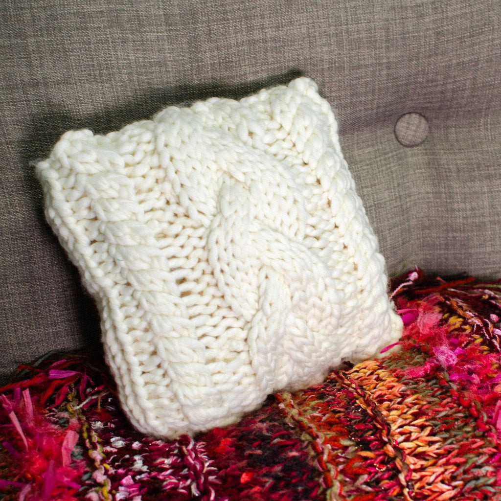 Off-white triple cable knit small square throw pillow on a minimalist neutral sofa
