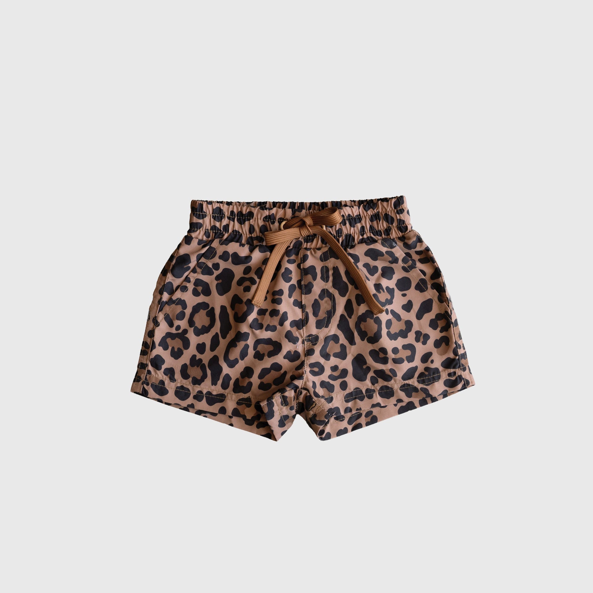Kids wearing classic tan and black leopard print board shorts at the beach