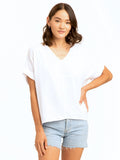 A woman wearing a flowy 100% organic cotton Honora Gauze V-Neck top with an elegant neckline.
