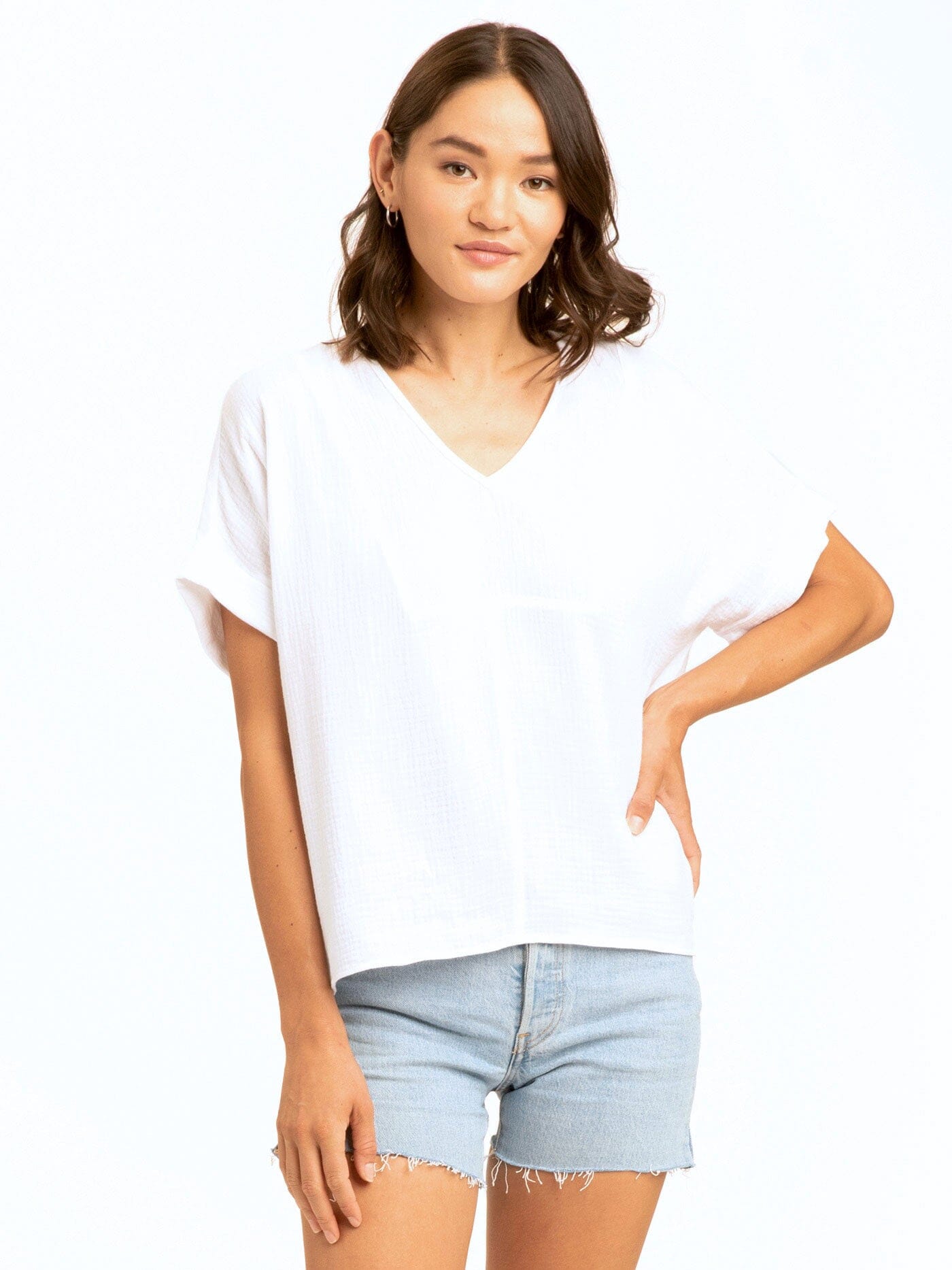 A woman wearing a flowy 100% organic cotton Honora Gauze V-Neck top with an elegant neckline.