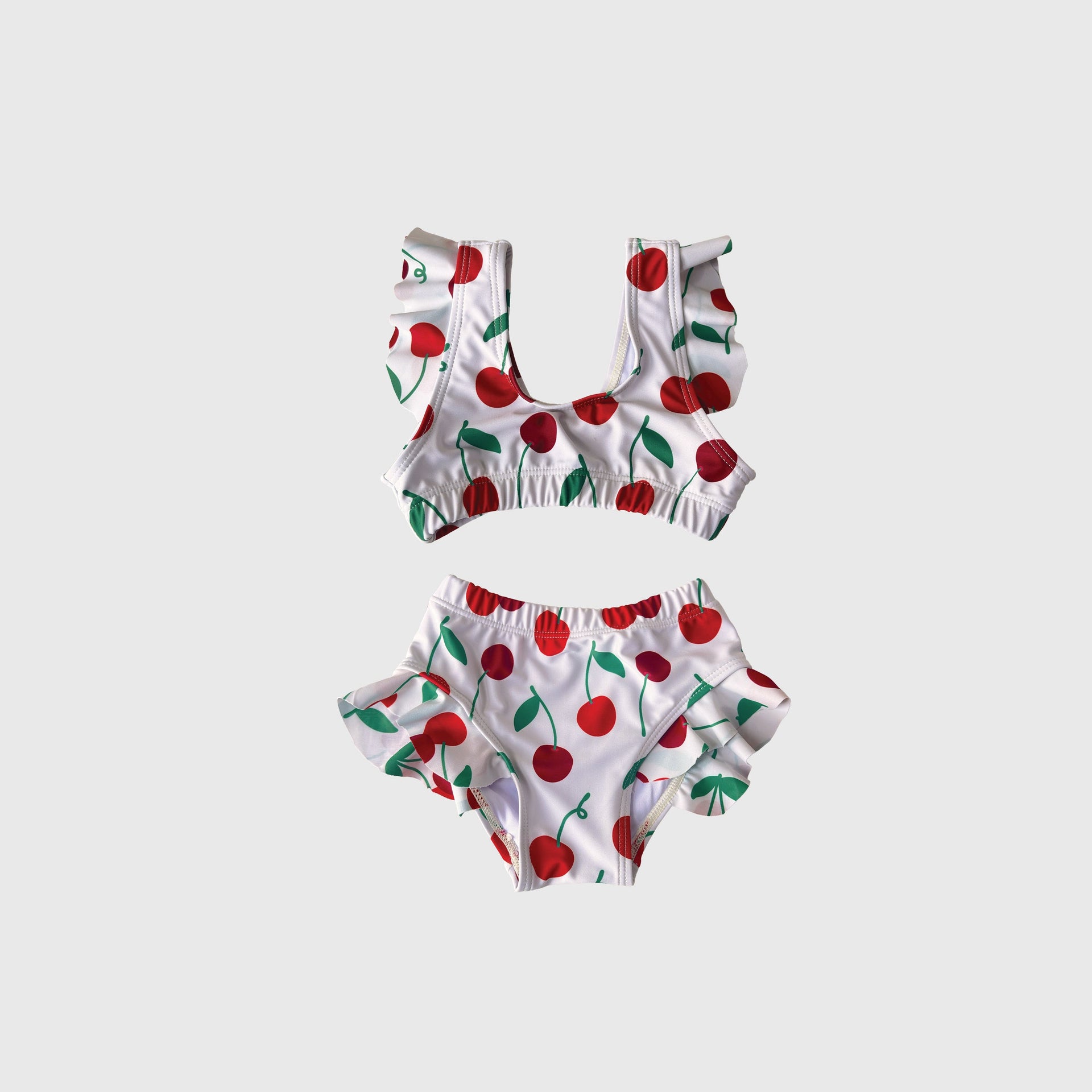 Girl's two-piece swimsuit featuring a cute cherry print on white background