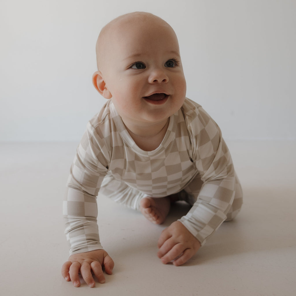 Child wearing a beige and cream geometric checkerboard footless lounge set.