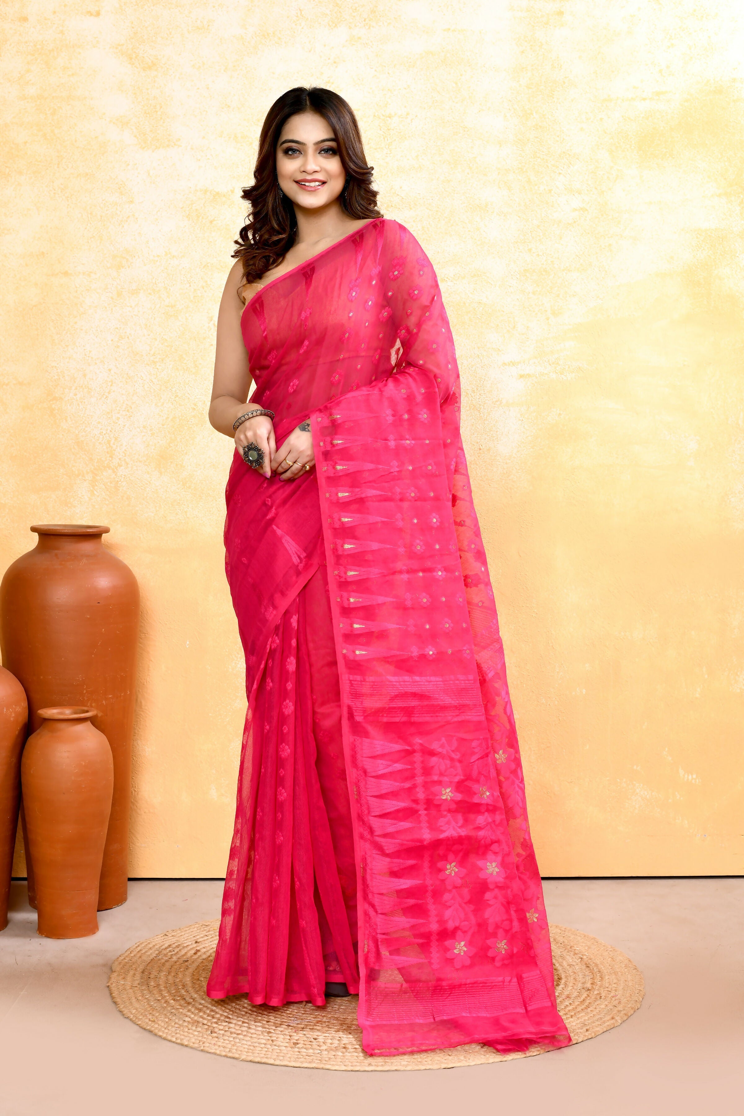 A close-up of a Rani Pink cotton blend Jamdani saree featuring detailed embellishments and traditional weaving.