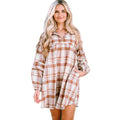 A woman wearing a brown and white plaid long sleeve mini dress with a relaxed fit.