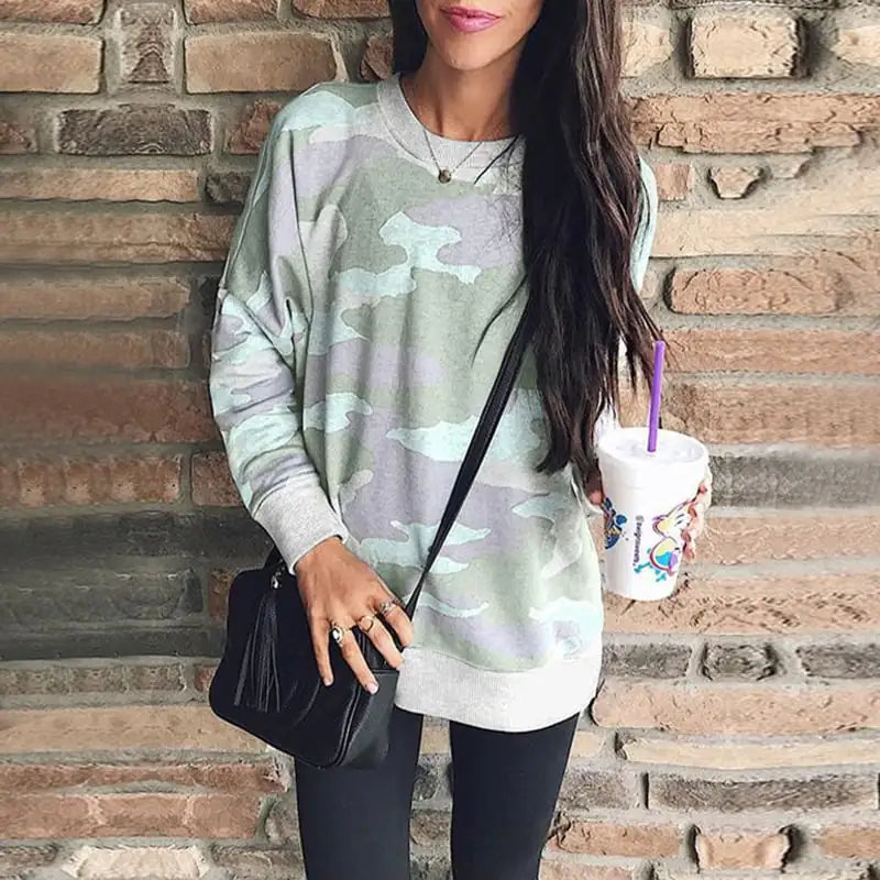 Woman wearing a loose fit camouflage print long sleeve round neck sweatshirt with ribbed cuffs