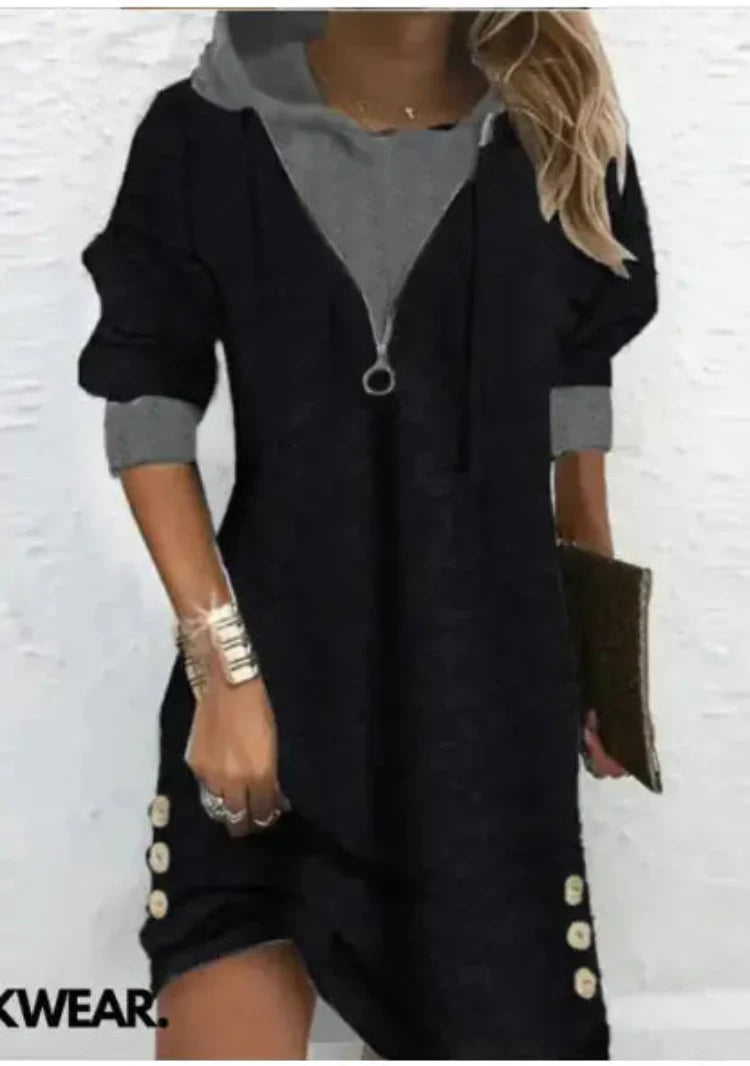 A woman wearing a hooded long sleeve patchwork dress with side button details and a zip-front closure.