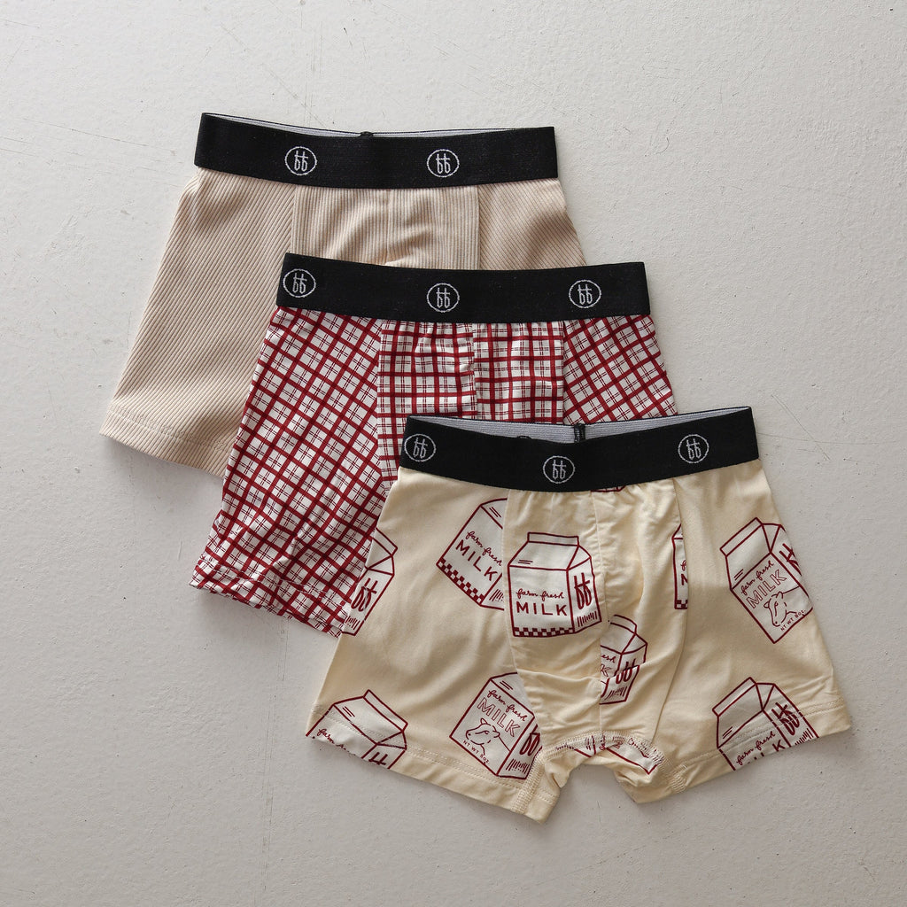 Three pairs of kids boxer briefs in window pane, milk carton, and ribbed cream prints with black branded elastic waistbands.