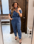Model wearing an off-shoulder blue and black leopard print short sleeve jumpsuit with a tapered leg