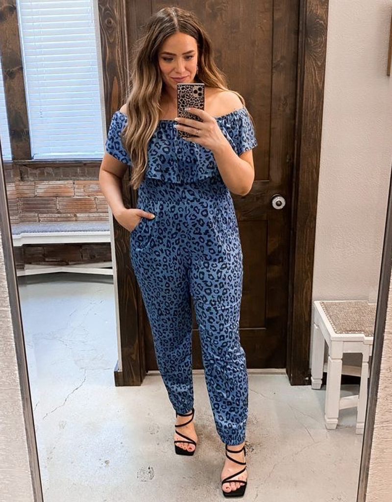 Model wearing an off-shoulder blue and black leopard print short sleeve jumpsuit with a tapered leg
