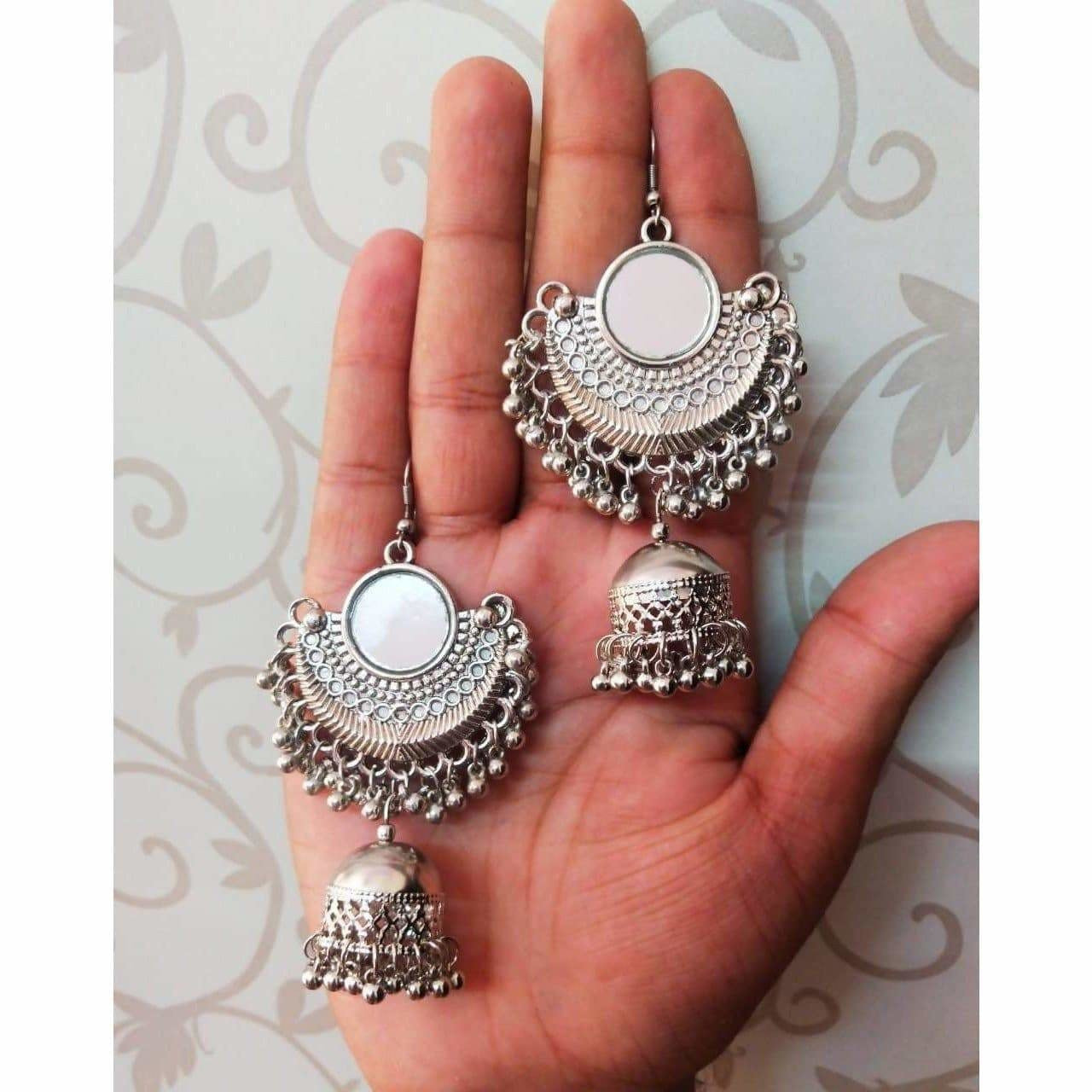 Bollywood style silver half-moon jhumki earrings with mirror work accents.