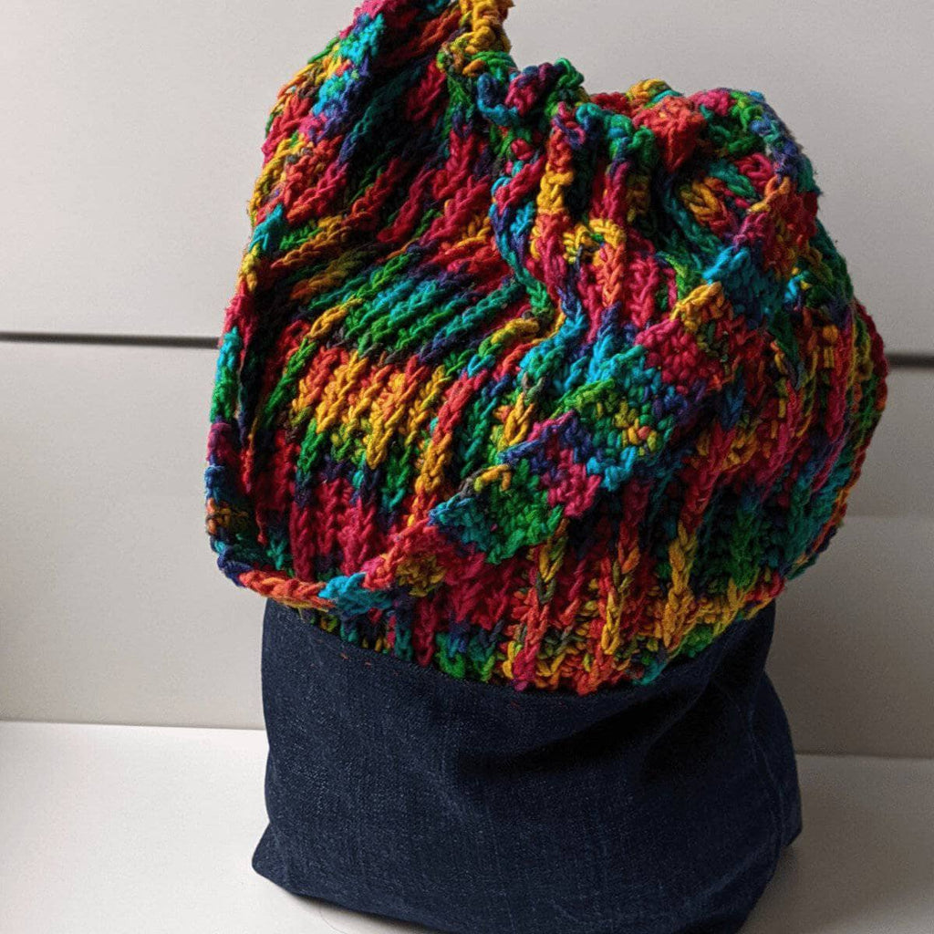 Upcycled denim shoulder bag with colorful yarn detailing, handmade bohemian aesthetic
