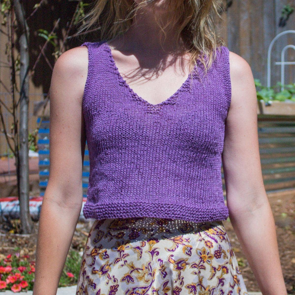 A woman wearing a handmade vibrant violet V-neck cropped tank top in a bohemian setting.