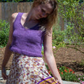 A woman wearing a handmade bohemian-style violet V-neck crop top in a bright summer setting.