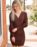 A woman wearing a deep chocolate brown long-sleeve V-neck sweater dress in a fitted mini silhouette
