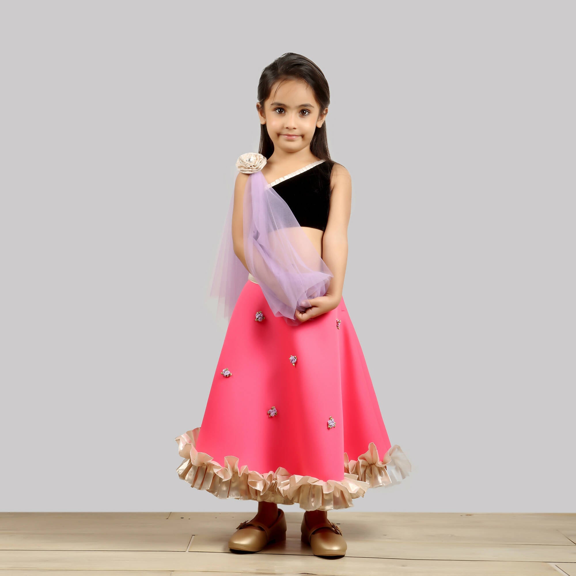 One-shoulder black choli with a pink scuba ghagra and net dupatta with gold flowers.