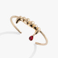 Silver cuff bracelet featuring sculpted vampire fangs and a small red teardrop charm against a neutral background.