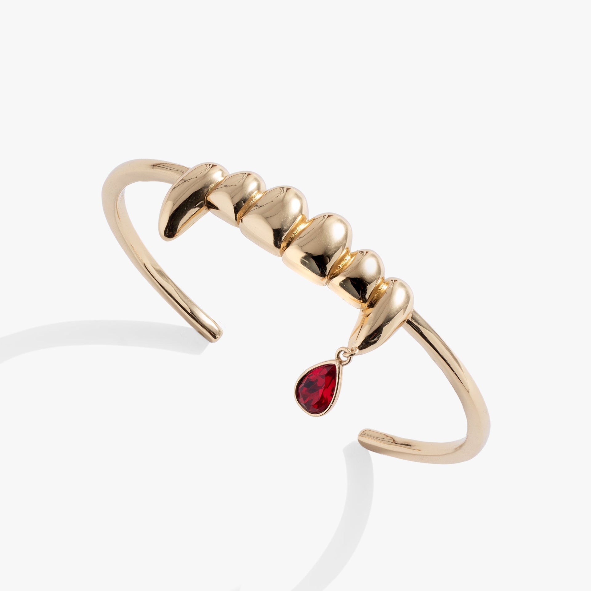 Silver cuff bracelet featuring sculpted vampire fangs and a small red teardrop charm against a neutral background.