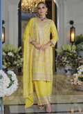 Woman wearing a vibrant yellow Chinon silk palazzo suit with intricate gold embroidery and gota patti detail.