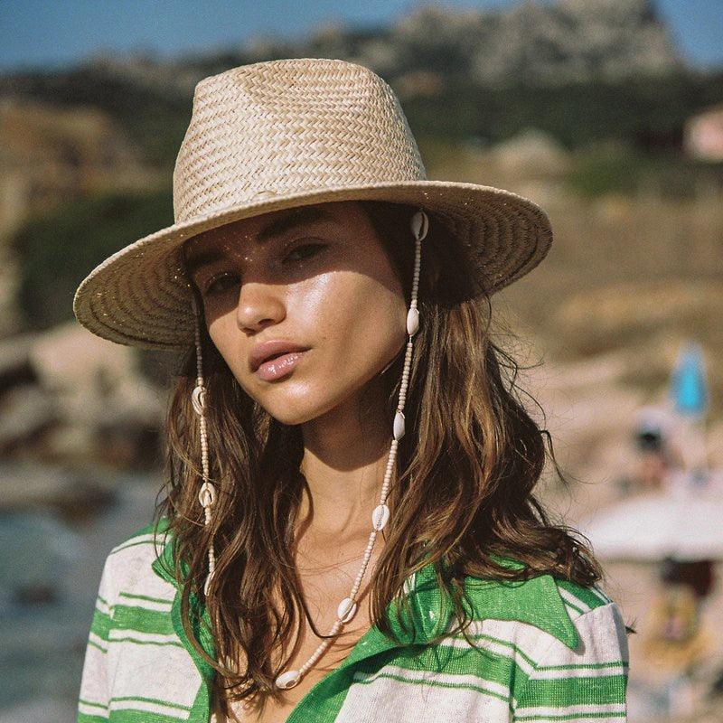 Elegant straw fedora with beaded seashell trim for a bohemian summer look.