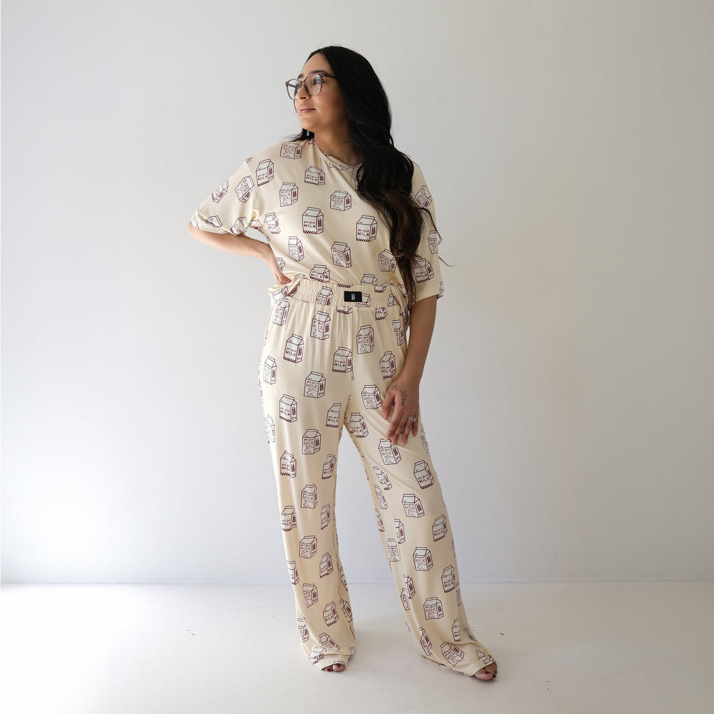 A woman wearing a beige matching lounge set with a milk carton print, consisting of a short-sleeved boxy tee and wide-leg lounge pants.