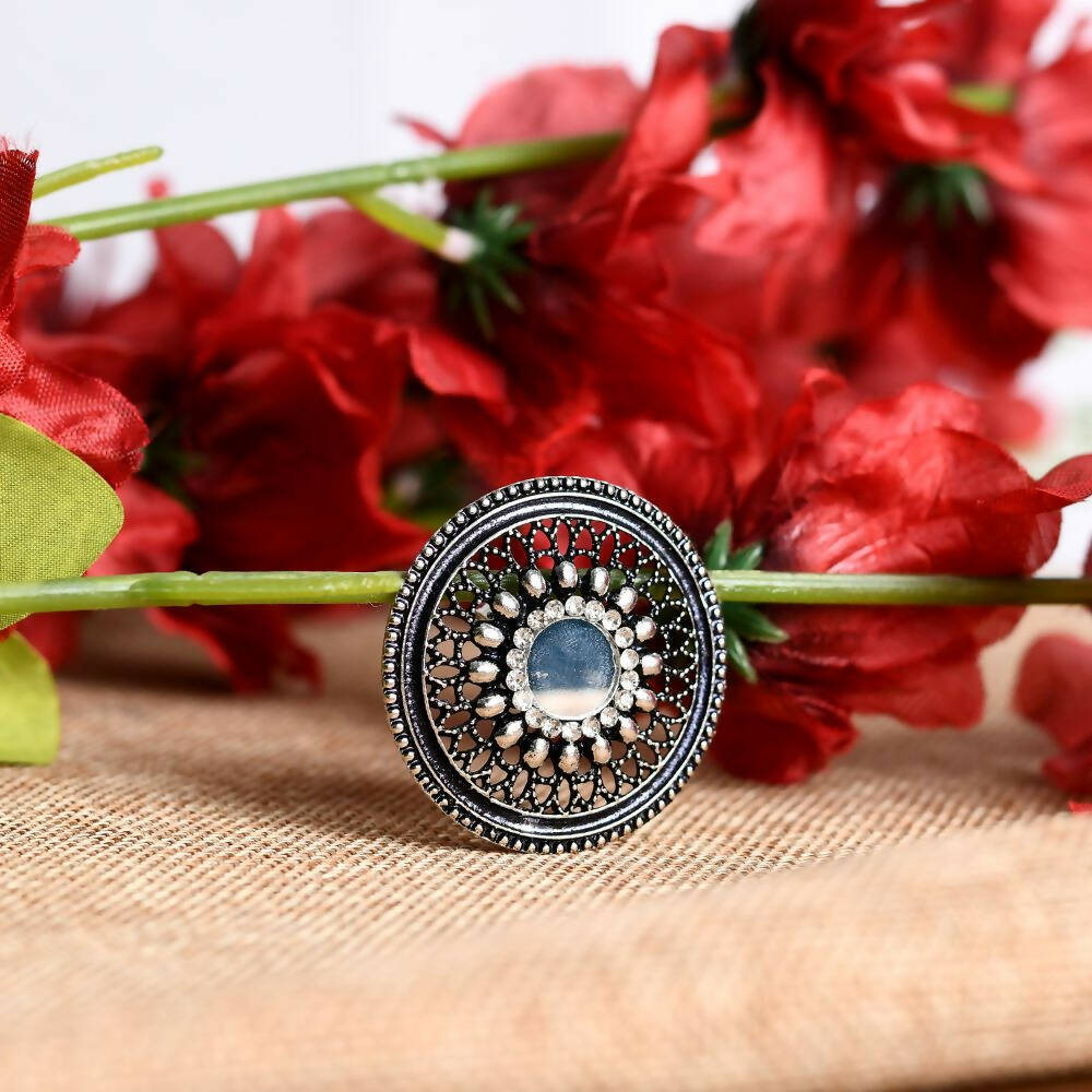 Close-up of a traditional oxidised silver-toned adjustable finger ring with intricate patterns.
