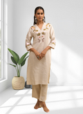 Woman wearing a beige linen long kurta with matching pants featuring detailed embroidery.