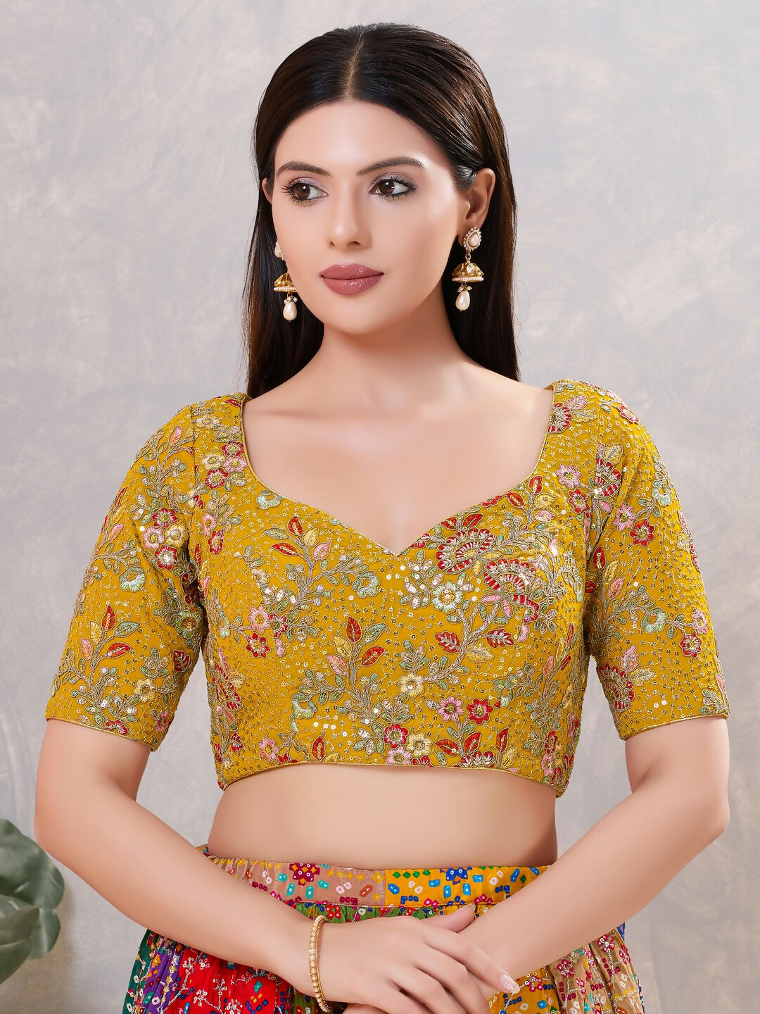 Woman wearing a mustard color silk stitched blouse with a sweetheart neckline