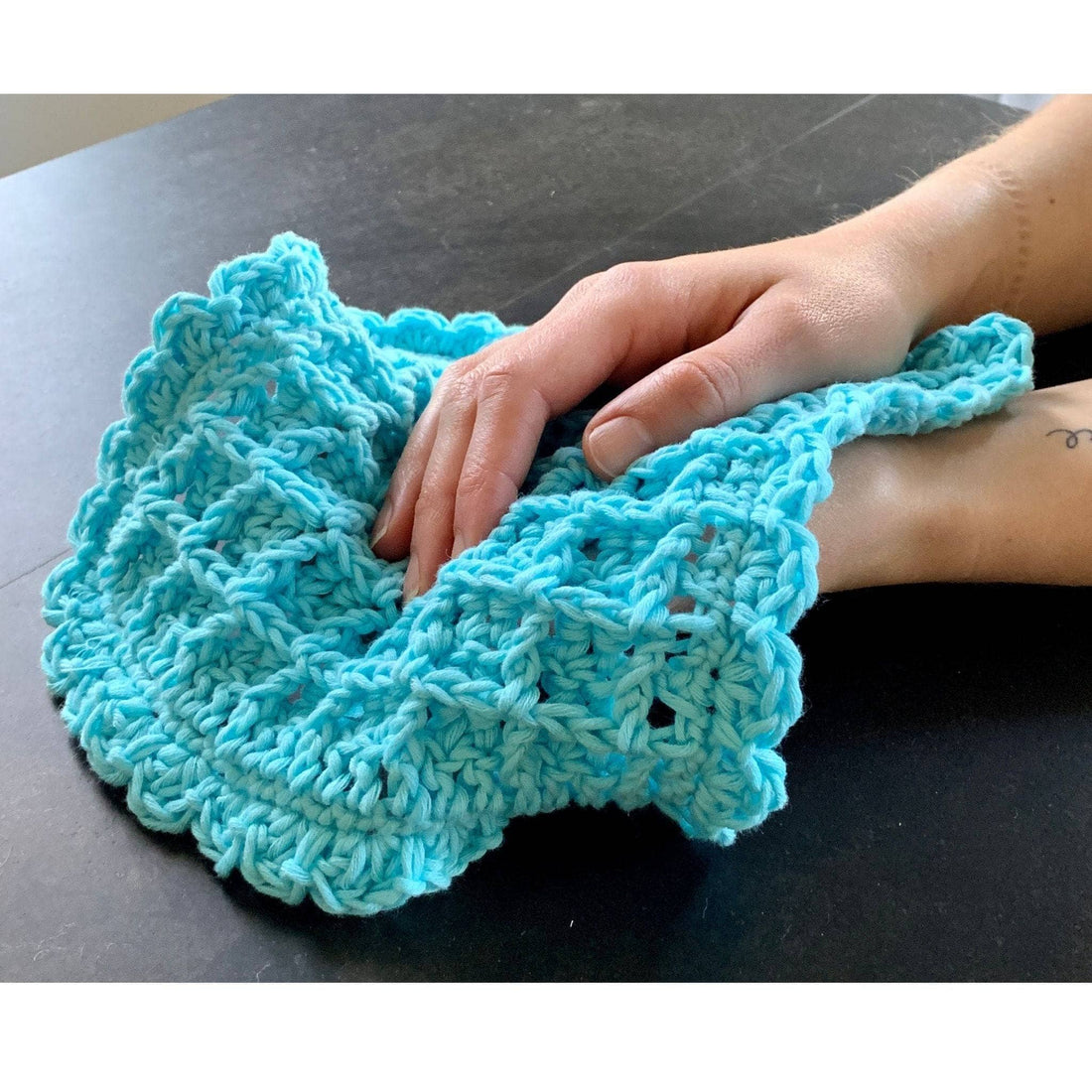Close up of a crochet washcloth featuring a textured waffle stitch pattern