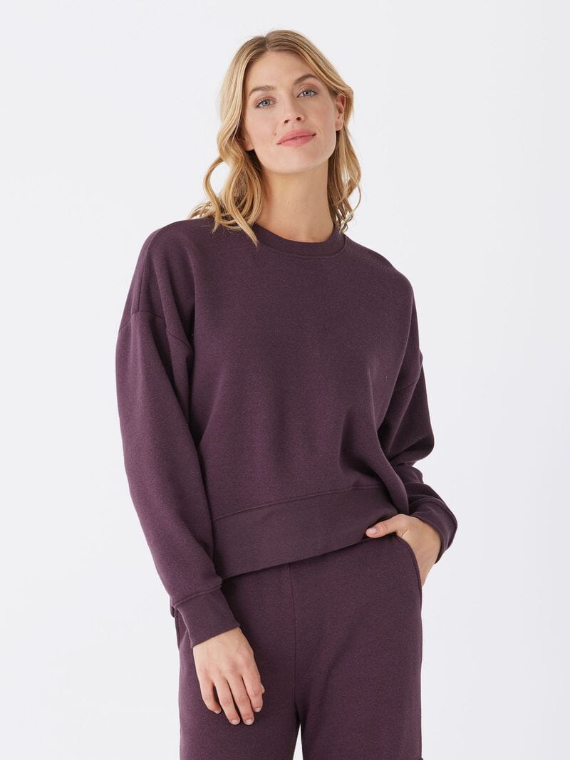 Woman wearing an oversized dark purple triblend fleece pullover with ribbed trim