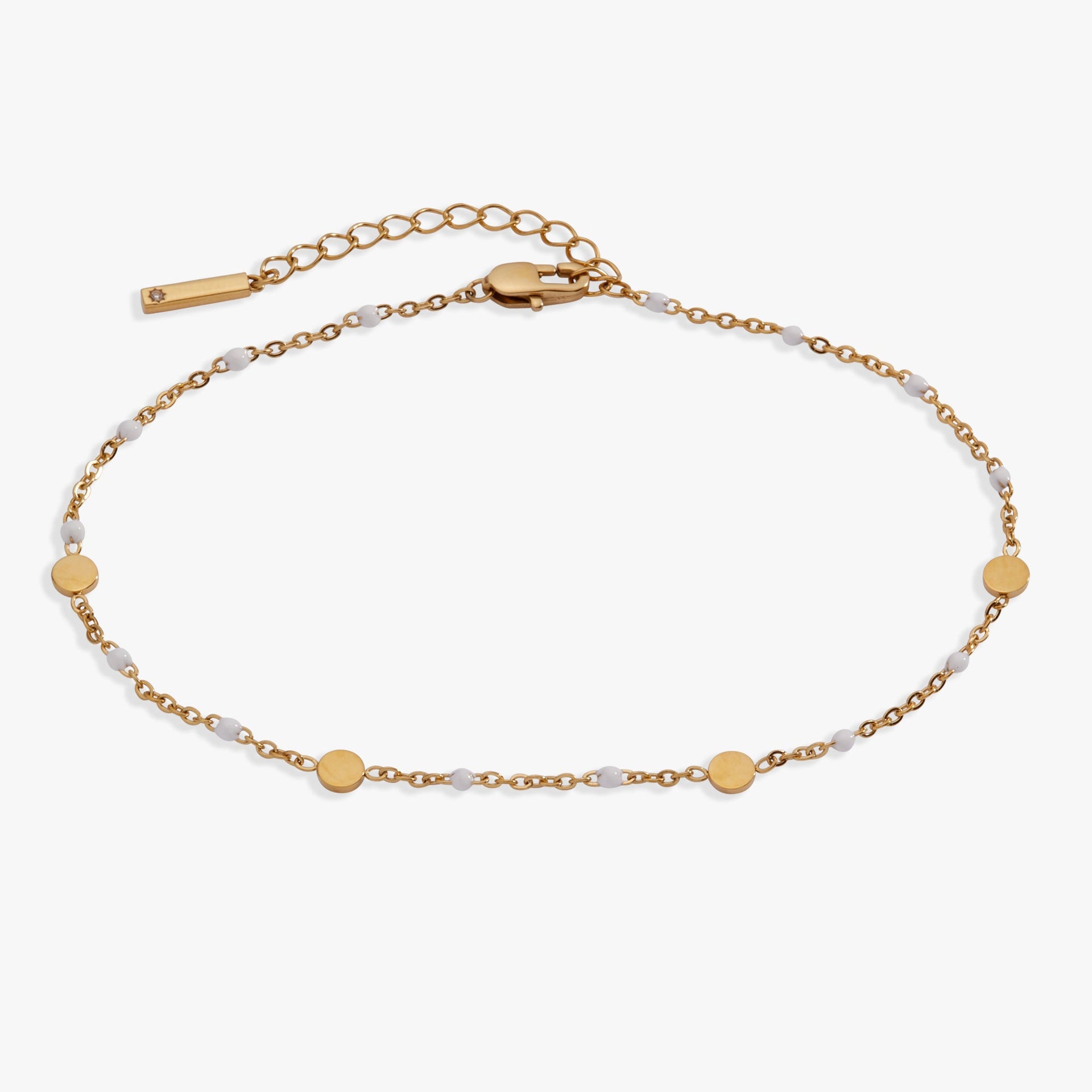 White enameled chain anklet with gold-plated coin stations on a light background
