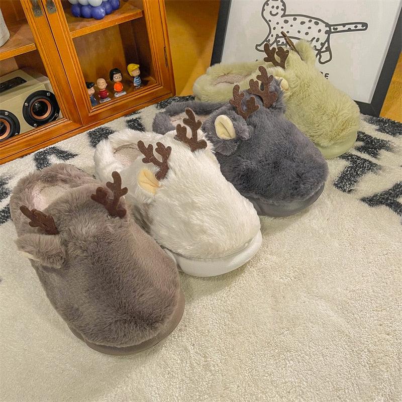 White plush animal slippers with cute antlers on a wooden floor