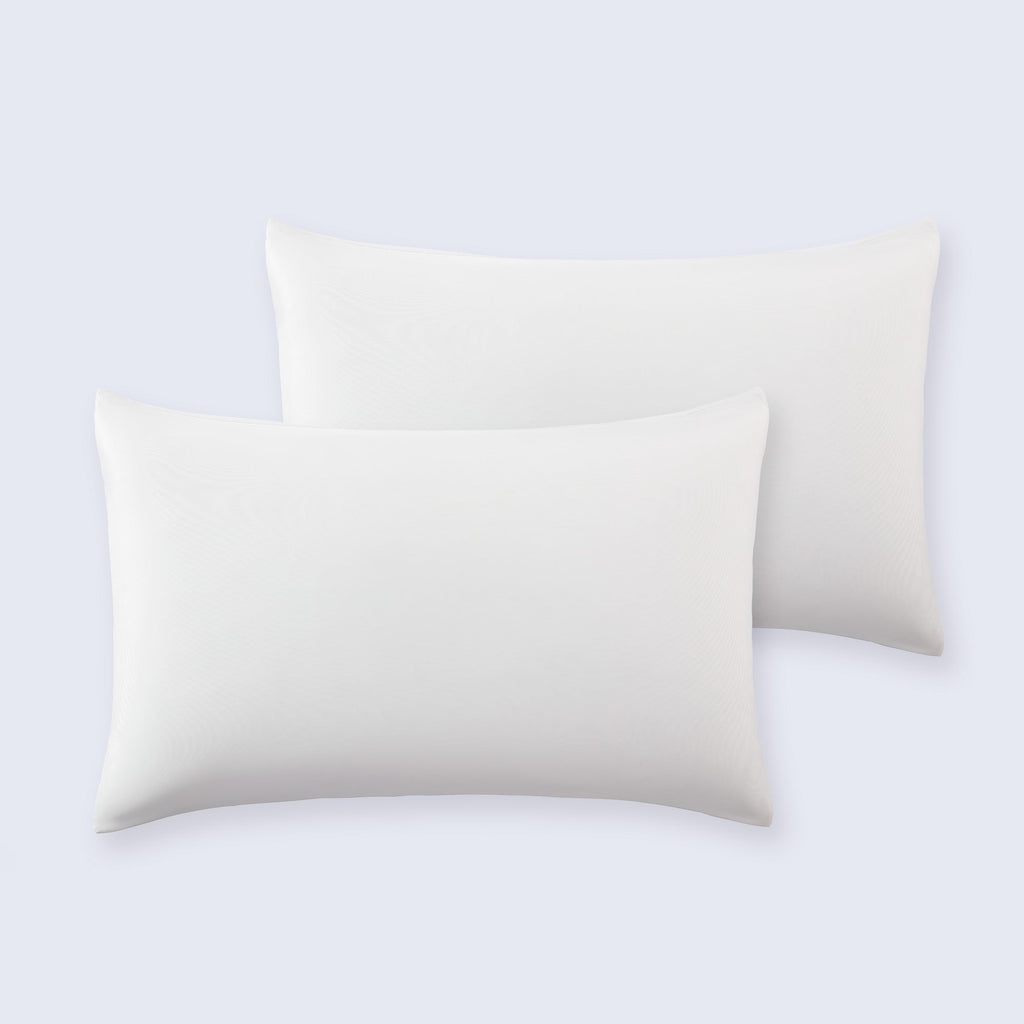 Set of two smooth white cooling pillowcases arranged neatly on a bed.