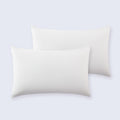 Set of two smooth white cooling pillowcases arranged neatly on a bed.