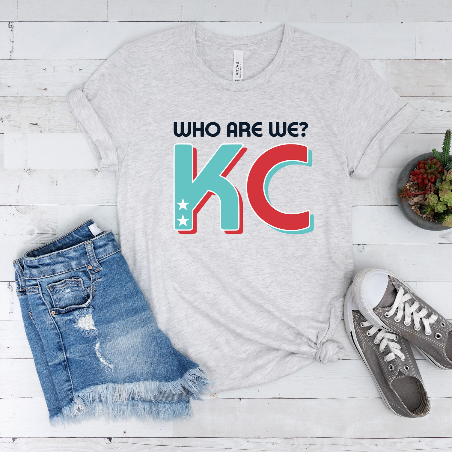 Who Are We KC graphic printed on ash grey Bella Canvas tee and sweatshirt
