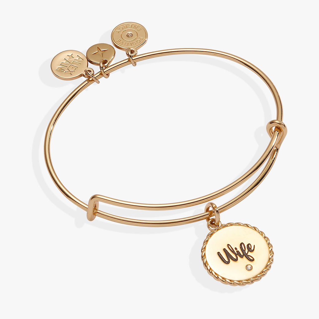 A minimalist Wife charm bangle in gold and silver with a clear crystal accent.