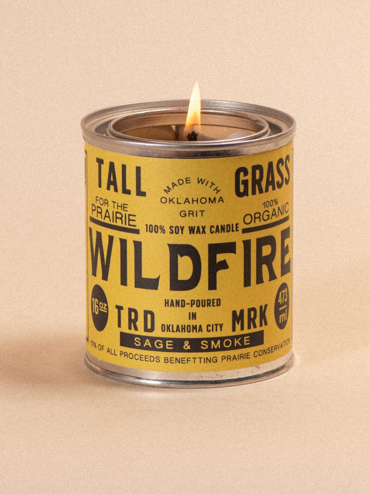 A 16 oz Wildfire Sage and Smoke soy wax candle in a yellow metal tin.
