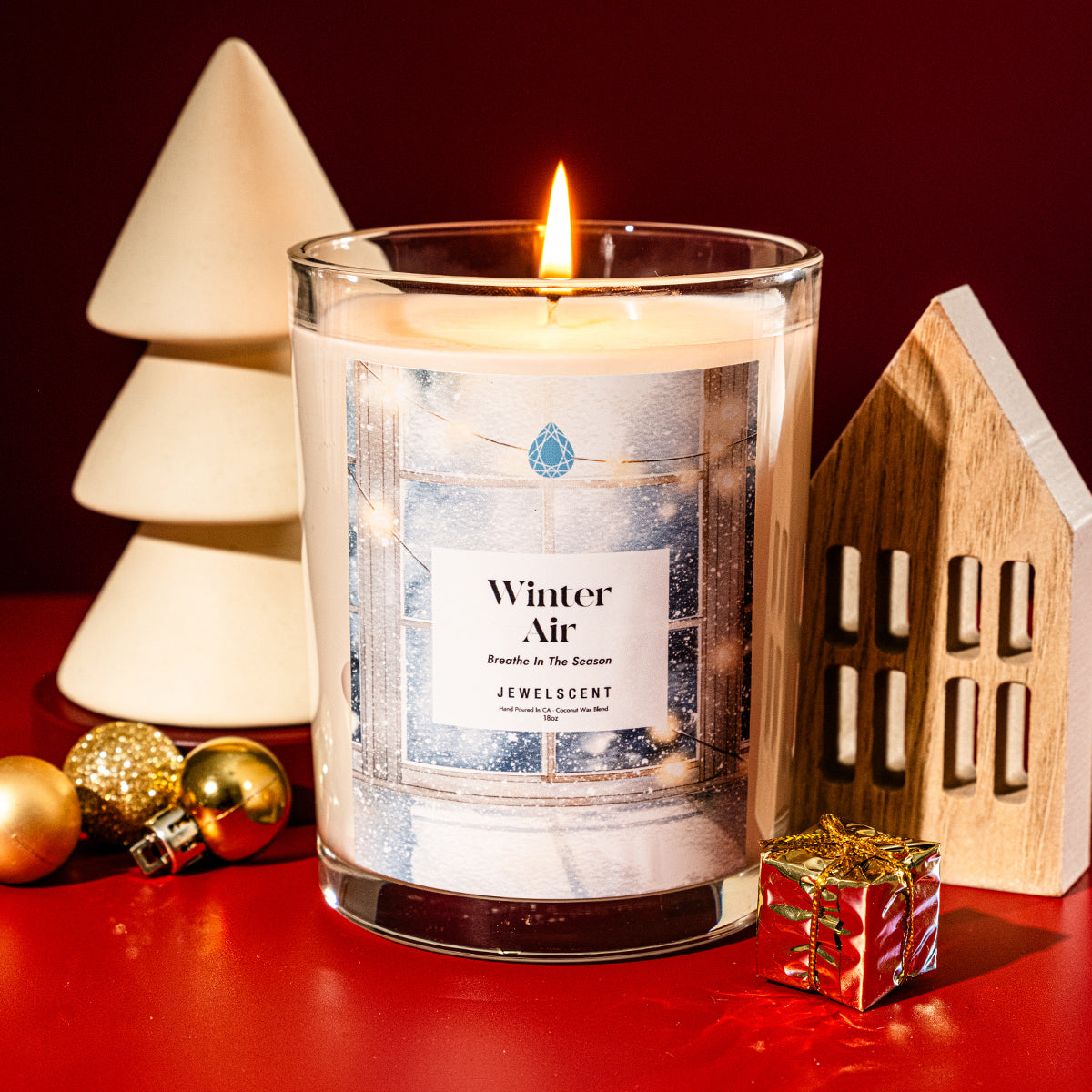 18oz Winter Air scented jewelry candle featuring a winter window scene label, displayed with holiday decor and a burning wick