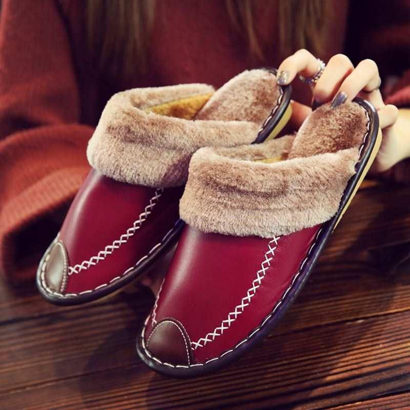 Unisex leather house slippers with plush faux fur lining in deep earth tones, featuring a non-slip sole.
