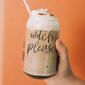 A 17oz clear glass cup with the text Witch Please printed on the side, complete with a bamboo lid and a stainless steel straw, filled with an iced coffee drink.