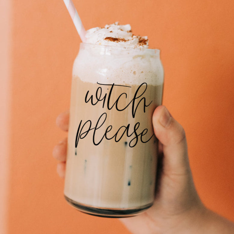 A 17oz clear glass cup with the text Witch Please printed on the side, complete with a bamboo lid and a stainless steel straw, filled with an iced coffee drink.