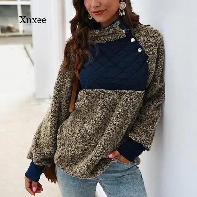 Woman wearing a beige fuzzy sherpa hoodie with a navy blue quilted chest panel and button details