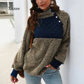 Woman wearing a beige fuzzy sherpa hoodie with a navy blue quilted chest panel and button details