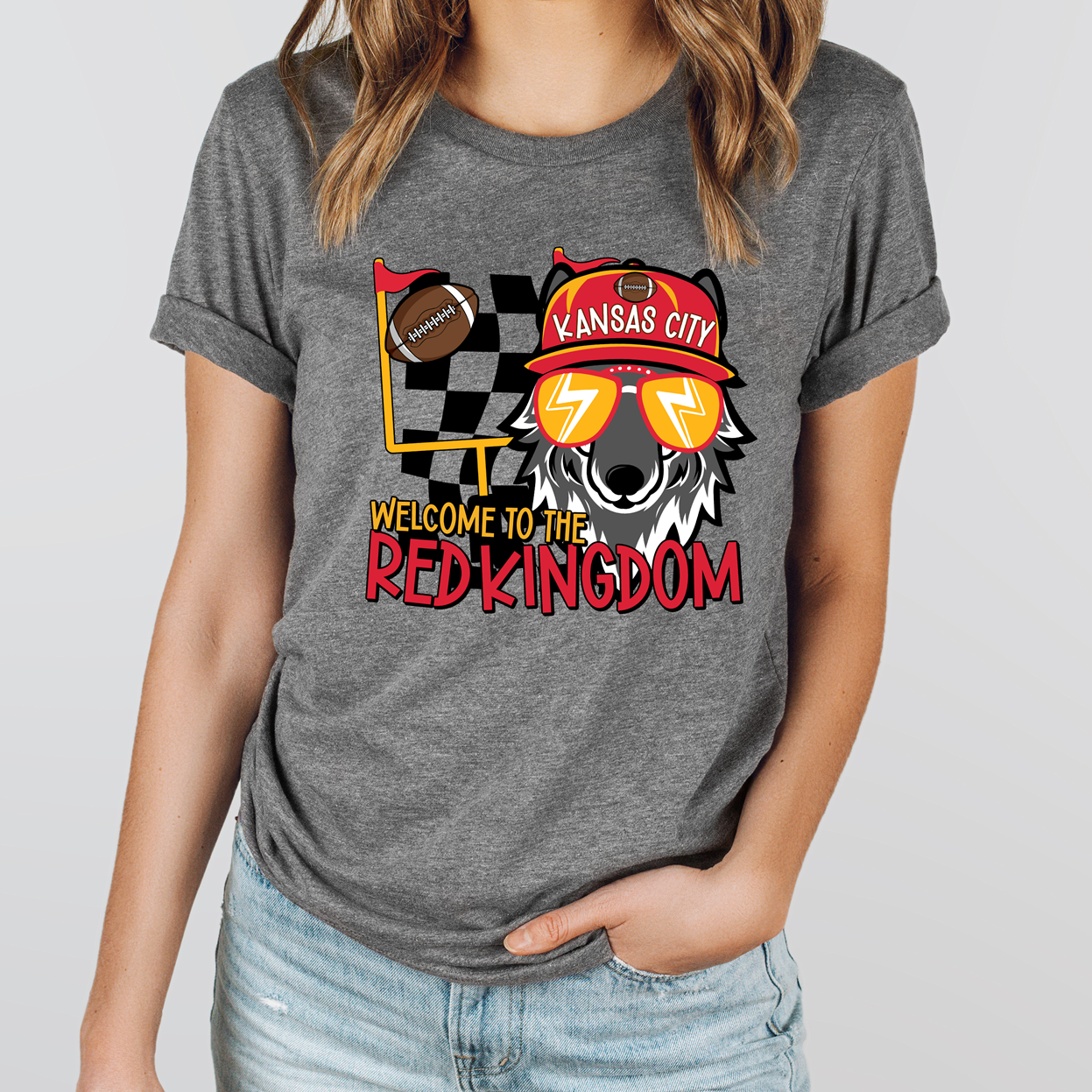 A grey graphic tee and sweatshirt featuring a cartoon wolf wearing a Red Kingdom football cap and sunglasses with the text Welcome to the Red Kingdom.