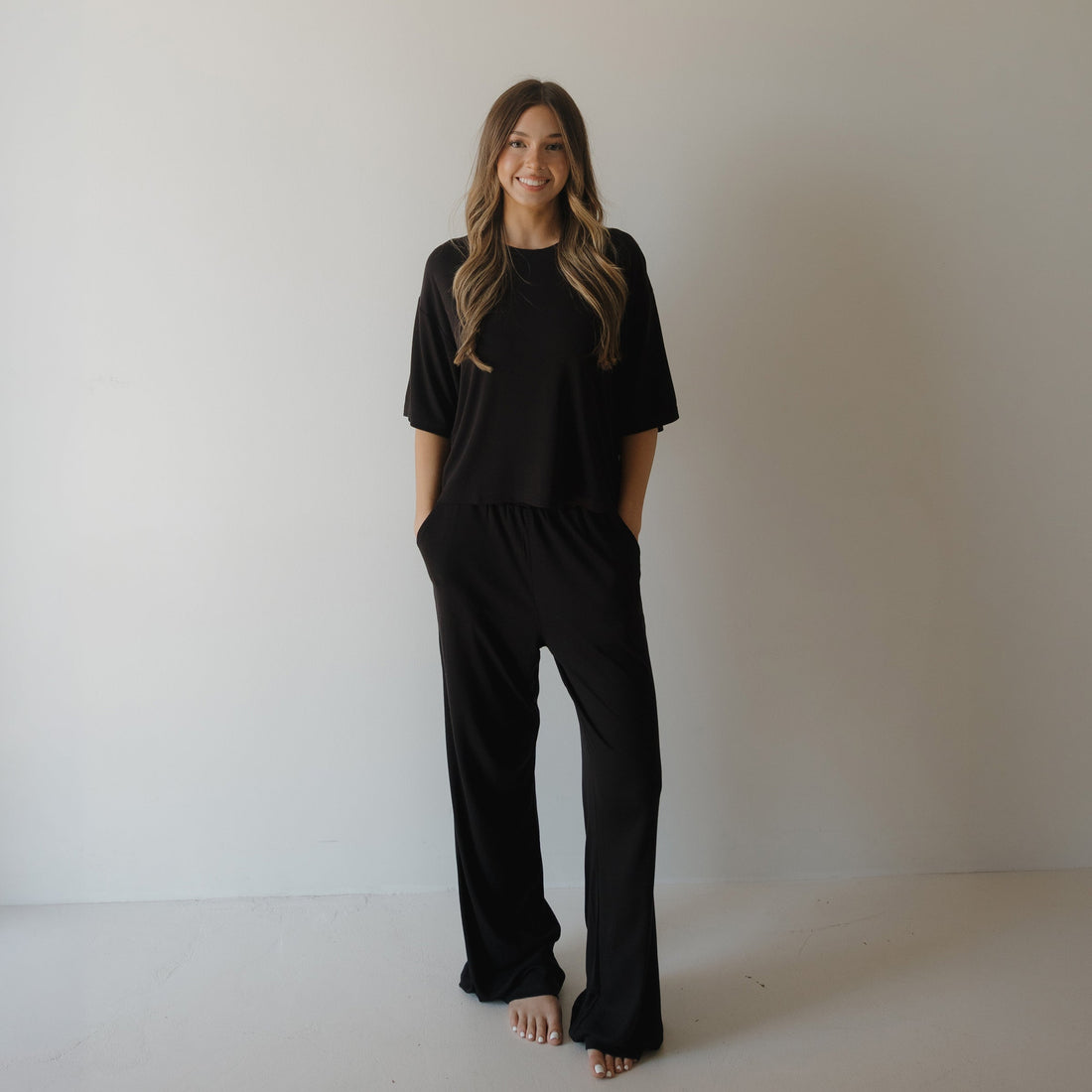 Woman wearing a comfortable ribbed black bamboo boxy tee and wide-leg lounge pants set.