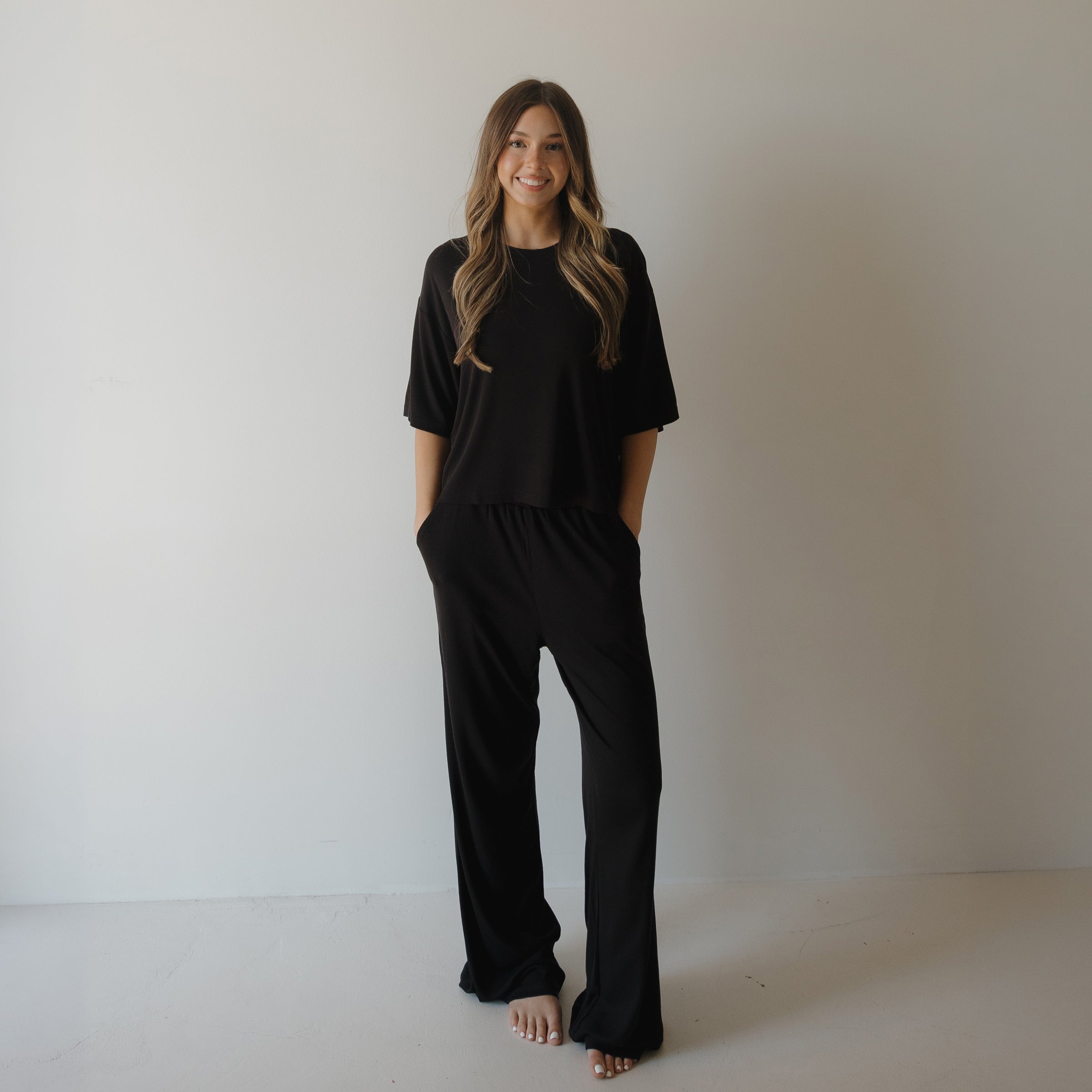 Woman wearing a comfortable ribbed black bamboo boxy tee and wide-leg lounge pants set.