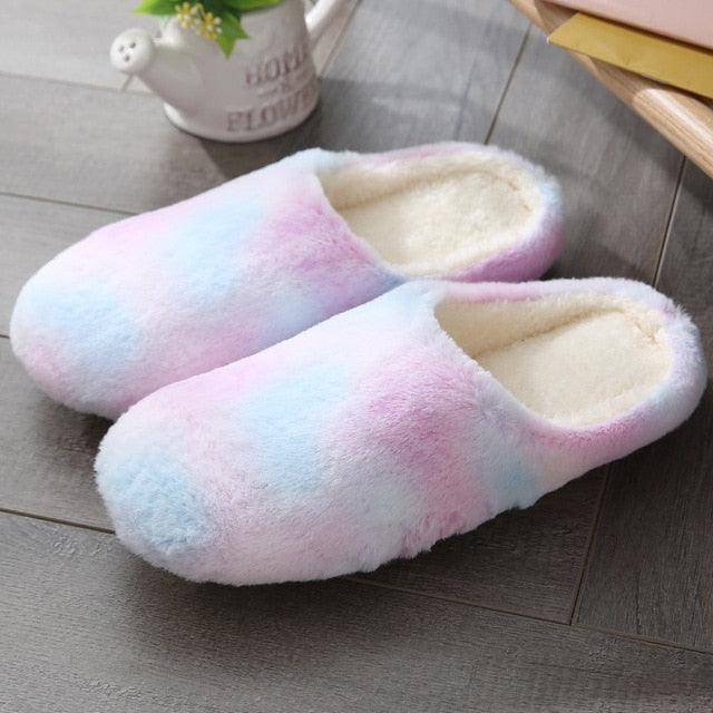 A pair of soft, pastel-colored plush indoor slippers on a clean, modern bedroom floor.