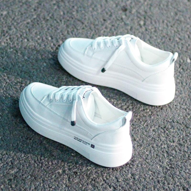 A pair of modern white women's leather vulcanized sneakers with lace-up closure.