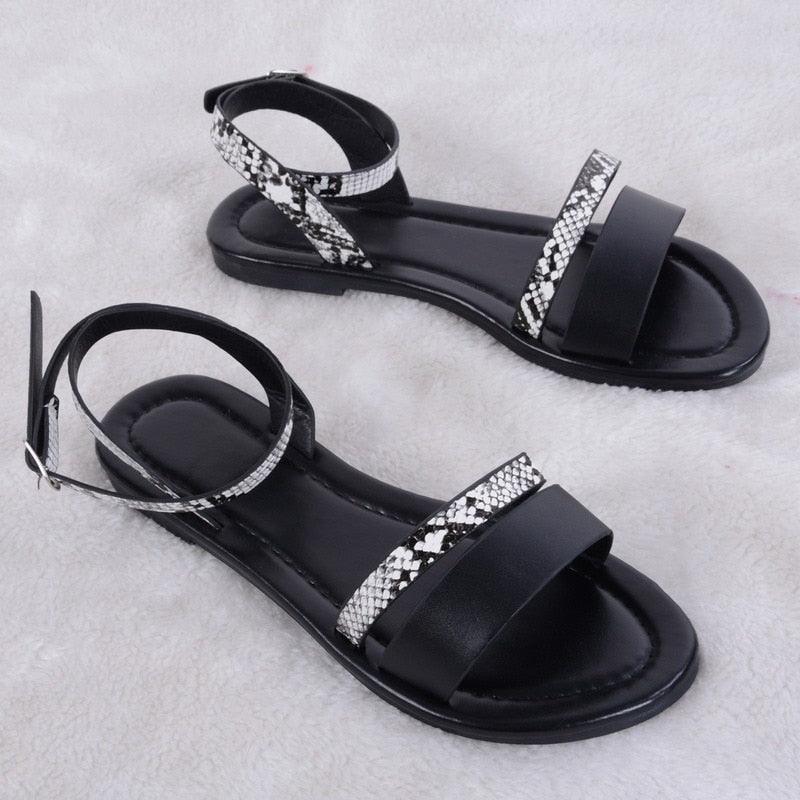 Close up of black luxury women's leather sandals with buckle straps and a comfortable slope design