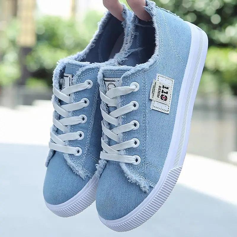 A pair of stylish blue canvas sneakers for women featuring contrasting stitching and white laces.