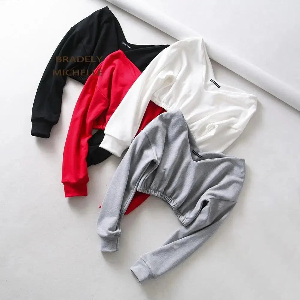 A woman wearing a deep V-neck long sleeve cropped sweatshirt with drop shoulders, styled for activewear.